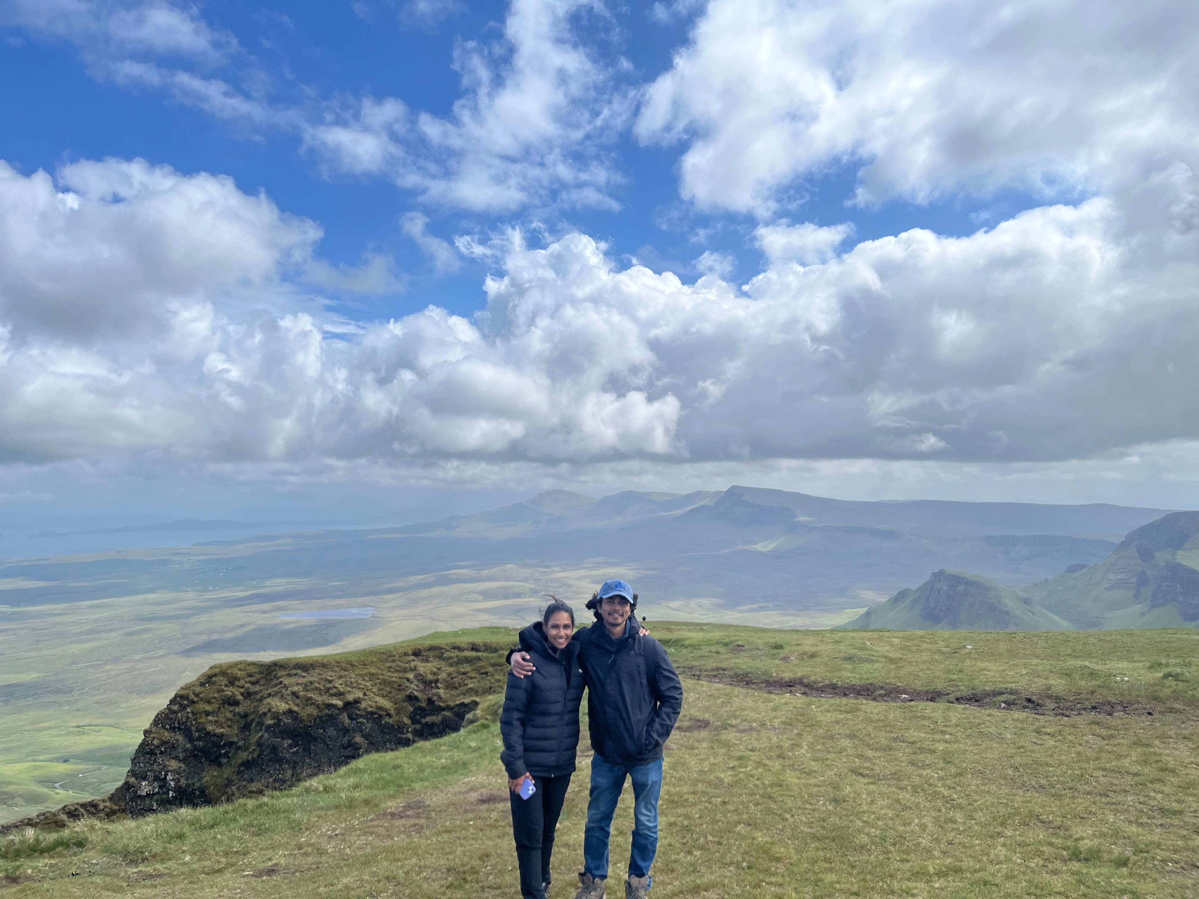 A landscape of the English countryside showing some flowers, a gated entry, and a small stone house. 